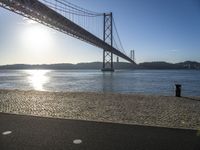 sun shines near the water and bridge over the water on a sunny day, with a sand beach next to it