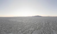 a beautiful view of some very small mountains in the distance is an icy body of water and a large snow field