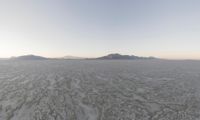 a beautiful view of some very small mountains in the distance is an icy body of water and a large snow field