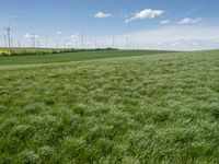 green grassy field with windmills and blue sky in background - image via istb com