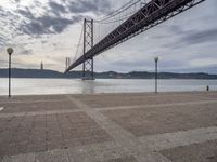 the large bridge over water is seen in this photograph shot of an empty walkway by the ocean