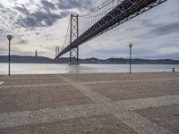 the large bridge over water is seen in this photograph shot of an empty walkway by the ocean