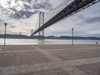 the large bridge over water is seen in this photograph shot of an empty walkway by the ocean