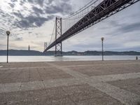 the large bridge over water is seen in this photograph shot of an empty walkway by the ocean