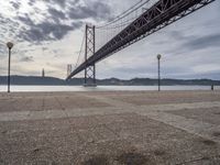 the large bridge over water is seen in this photograph shot of an empty walkway by the ocean