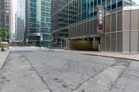 an empty street has many glass buildings next to it in this big city area there is a building on the corner that's on the left side