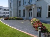 a tall building with a white picketer and walkway through it and many potted flowers on the lawn