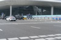traffic moves past the front of an airport terminal where there is only one passenger on the bus