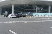 traffic moves past the front of an airport terminal where there is only one passenger on the bus