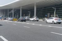 traffic moves past the front of an airport terminal where there is only one passenger on the bus