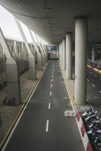 the view of the airport from an above floor area looking into a long walkway next to a parked cars and buildings