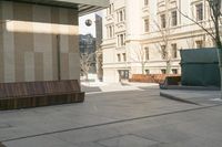 a sidewalk in a town that has benches on both sides of it with buildings in the background