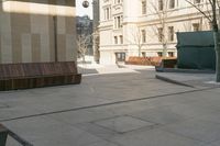 a sidewalk in a town that has benches on both sides of it with buildings in the background