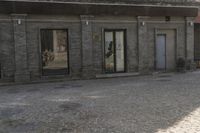 the person is walking down the street near old buildings on a sunny day with a red umbrella
