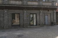 the person is walking down the street near old buildings on a sunny day with a red umbrella