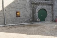 the person is walking down the street near old buildings on a sunny day with a red umbrella