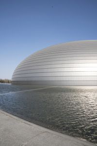 a person on a skateboard in front of a big building with a curved roof