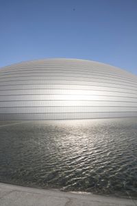 a person on a skateboard in front of a big building with a curved roof