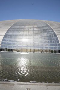 a person on a skateboard in front of a big building with a curved roof