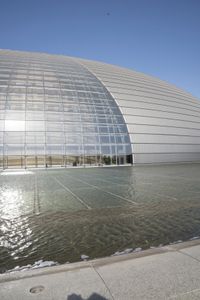 a person on a skateboard in front of a big building with a curved roof