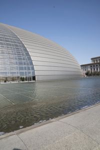 a person on a skateboard in front of a big building with a curved roof