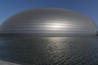 a person on a skateboard in front of a big building with a curved roof