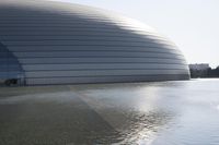 a person on a skateboard in front of a big building with a curved roof