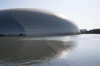 a person on a skateboard in front of a big building with a curved roof