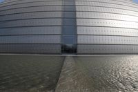 a person on a skateboard in front of a big building with a curved roof