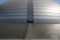 a person on a skateboard in front of a big building with a curved roof