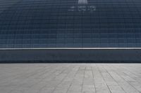 a person on a skateboard in front of a big building with a curved roof