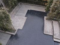 an empty pool in a patio with bamboos growing behind it and a brick wall