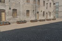 the person is walking down the street near old buildings on a sunny day with a red umbrella
