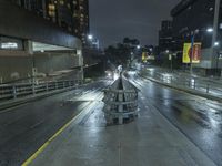 a bench that is sitting in the middle of the street on a wet road at night