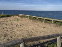 a bench sitting near a fence near the ocean in californian country style by the beach