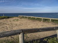 a bench sitting near a fence near the ocean in californian country style by the beach