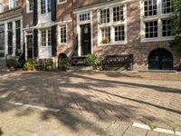 benches near a red brick building in a town square setting with trees, foliage and sunlight