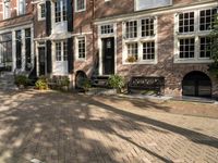 benches near a red brick building in a town square setting with trees, foliage and sunlight