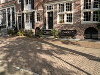 benches near a red brick building in a town square setting with trees, foliage and sunlight