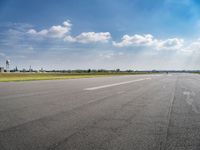 the empty runway at an airport with many planes on it's runways and water tanks in the background