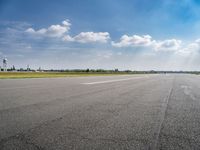 the empty runway at an airport with many planes on it's runways and water tanks in the background
