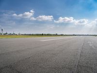 the empty runway at an airport with many planes on it's runways and water tanks in the background