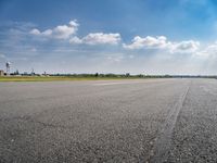 the empty runway at an airport with many planes on it's runways and water tanks in the background