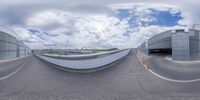 a fish eye lens view of an airport parking garage and ramp area with a blue cloudy sky overhead