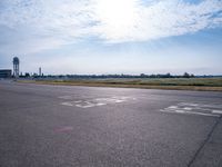 a car drives along an airport road past a water tower and wind vanes, in the sunlight