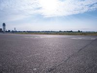 a car drives along an airport road past a water tower and wind vanes, in the sunlight