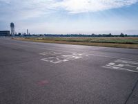 a car drives along an airport road past a water tower and wind vanes, in the sunlight