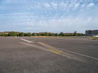 an airport runway with yellow lines painted on it and buildings behind them, in the distance