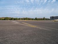 an airport runway with yellow lines painted on it and buildings behind them, in the distance