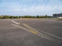 an airport runway with yellow lines painted on it and buildings behind them, in the distance